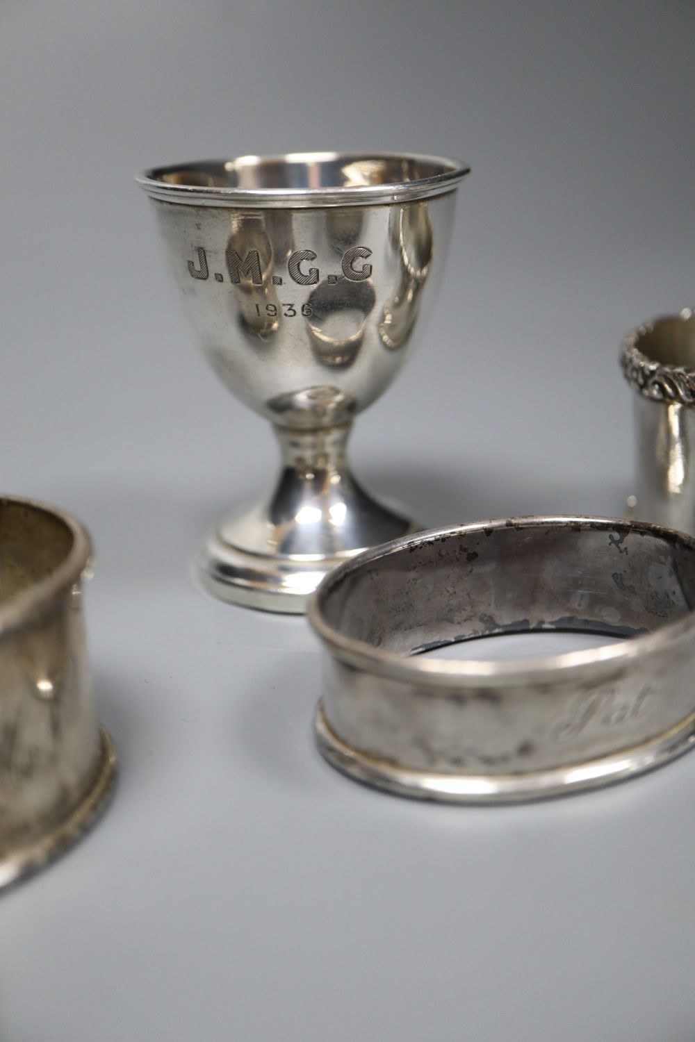 A pair of silver napkin rings, four other silver napkin rings and a small plated trophy cup.